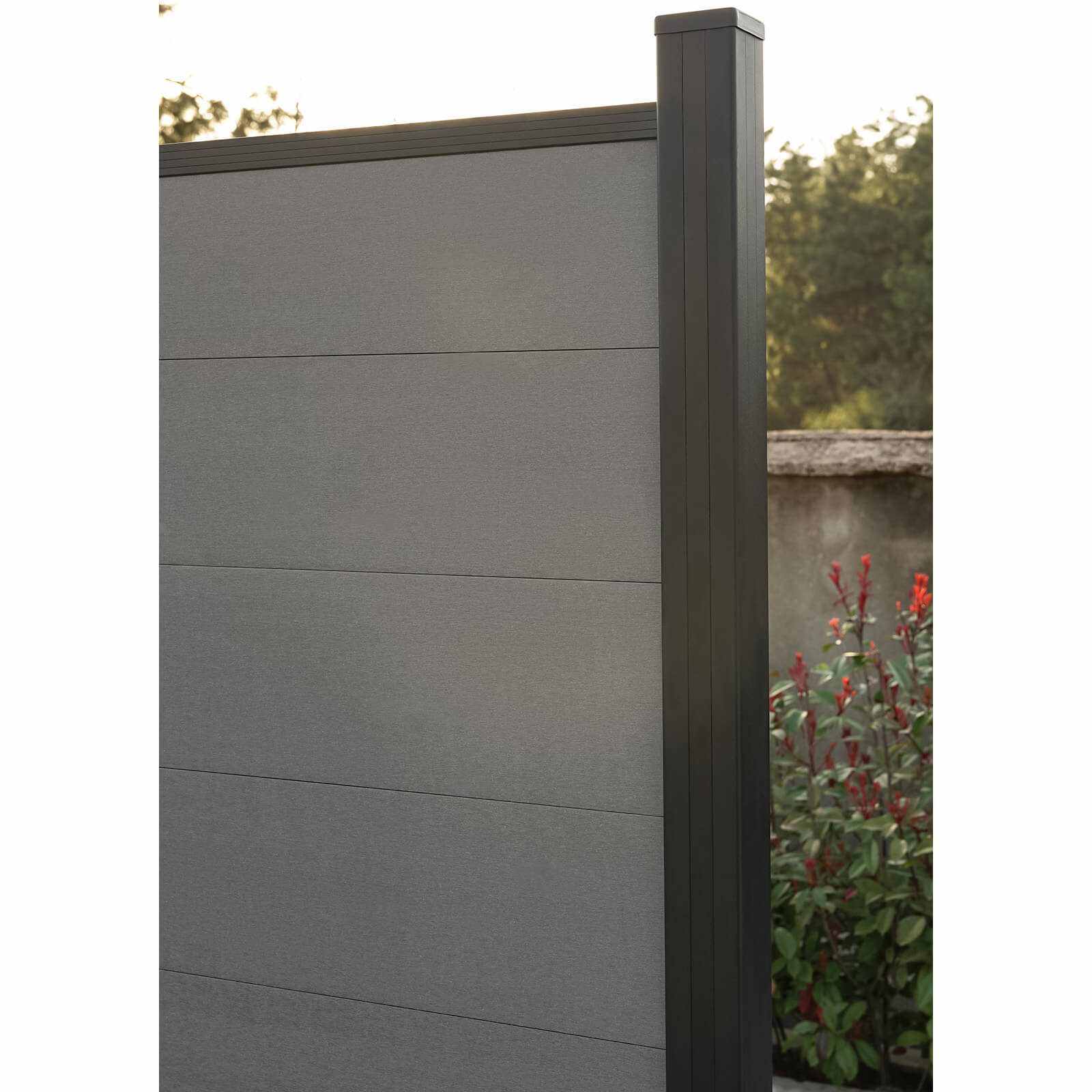 Silver-gray composite fence with wood grain texture, installed vertically on a stone foundation, available in NJ.