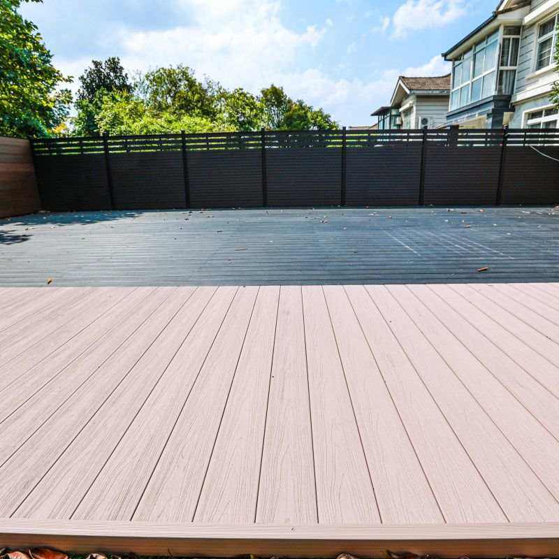 Light brown walnut composite deck planks with smooth surface, dark brown fence, blue sky, ideal for NJ outdoor spaces.