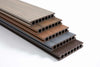 Stack of teak composite deck boards in light brown, dark brown, grey, and reddish brown with grooved surface, available in